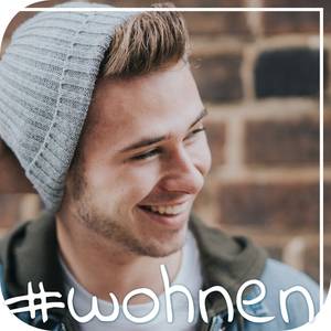 Quelle: Foto von Jeremy Mc Knight auf unsplash Junger Mann mit Mütze steht vor eine Backsteinwand und lacht.